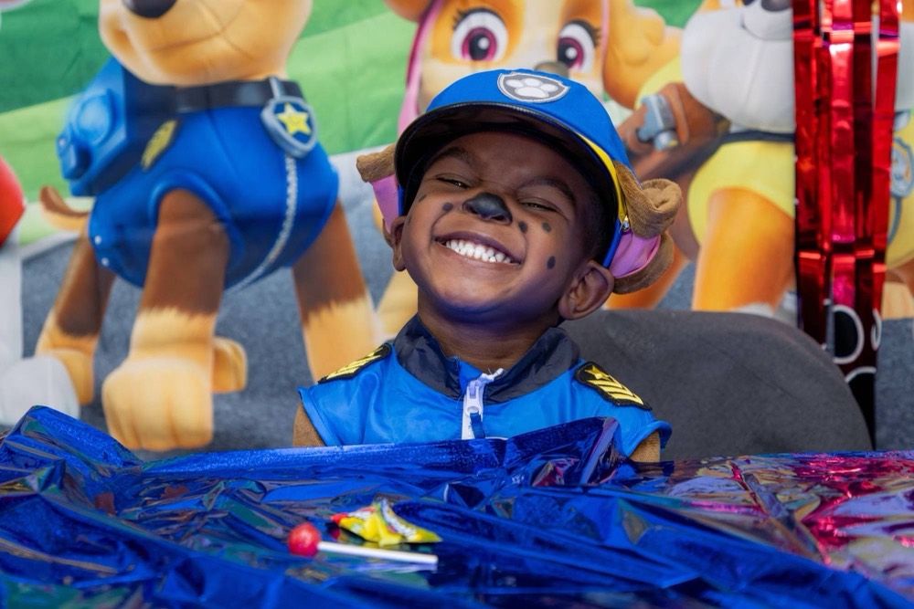 A joyful child with pup face paint at a candy-filled trunk