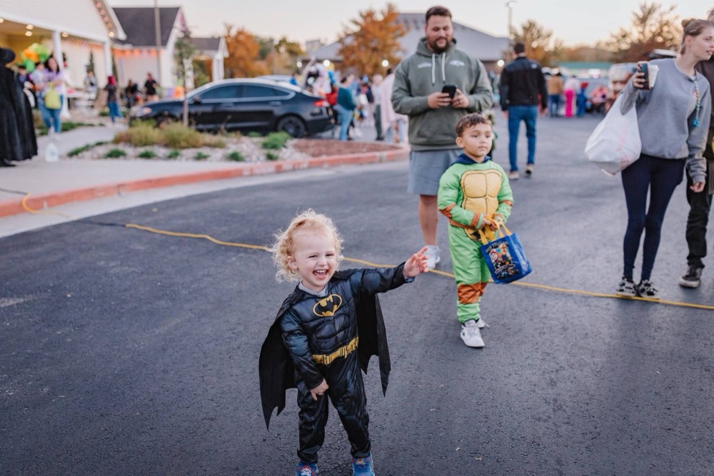 Costumed kids trick-or-treating among decorated trunks at a past event